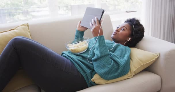 Happy African American Wanita Berbaring Sofa Earphone Menggunakan Tablet Dan — Stok Video
