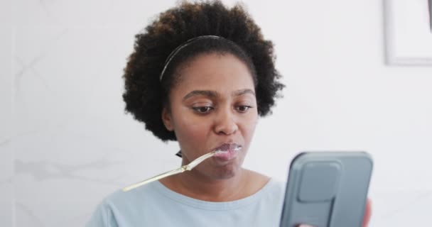 Wanita Afrika Amerika Menggosok Gigi Dan Menggunakan Smartphone Kamar Mandi — Stok Video