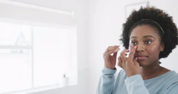 Mulher Americana Africana Feliz Aplicando Sob Máscara Ocular Olhando Espelho — Vídeo de Stock
