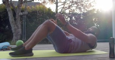Odaklanmış Afro-Amerikan erkek fitness eğitimi güneşli bahçede mekik çekerek ağır çekimde. Refah, zindelik ve sağlıklı yaşam tarzı, değişmedi..
