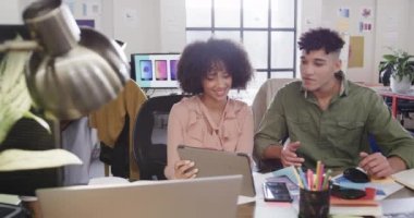 İki farklı yaratıcı tasarımcı günlük ofiste, tablette tartışıyorlar, ağır çekimde. Günlük ofis takım çalışması, iş, tasarım ve yaratıcı çalışma, değiştirilmemiş.