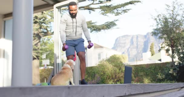 アフリカ系アメリカ人の男性のフィットネストレーニング日当たりの良い庭でデッキの重みで運動 スローモーション フィットネス 健康的なライフスタイル 変わらない — ストック動画