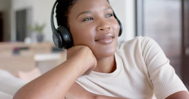 Счастливая Африканская Американка Сидящая Диване Наушниках Слушающая Музыку Замедленная Съемка — стоковое видео