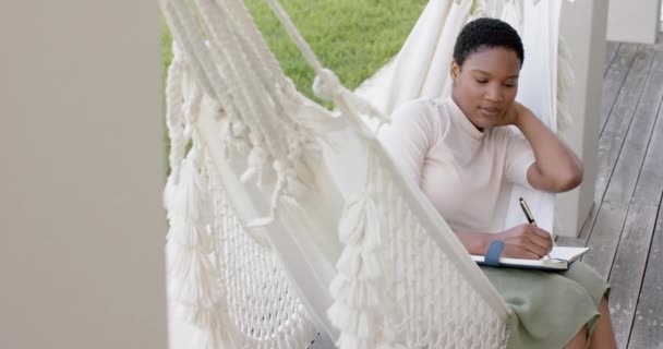 Happy African American Woman Sitting Hammock Terrace Writing Notebook Slow — Stok Video