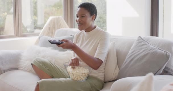 Счастливая Африканская Американка Сидит Диване Смотрит Телевизор Ест Попкорн Замедленная — стоковое видео