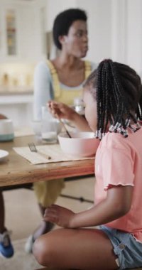 Afro-Amerikan bir kızın yemek odasında ağır çekimde eğlendiğinin dikey videosu. Yemek, yemek pişirme, yaşam tarzı, aile, birliktelik ve aile hayatı, değişmedi..