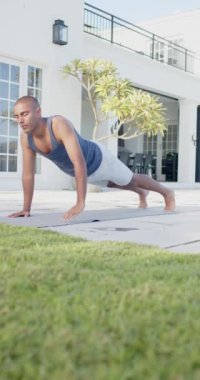 Sunny Garden 'da yoga yapan Anglo Hintli adamın dikey videosu, yavaş çekim. Kobra pozu, yaz, refah, zindelik ve sağlıklı yaşam tarzı, değişmemiş..