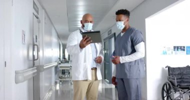 Çeşitli doktorlar işi tartışıyor ve hastanenin koridorunda tablet kullanıyorlar, ağır çekimde. Hastane, takım çalışması, iletişim, tıp, sağlık ve iş, değiştirilmemiş.