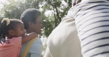 Oğlu ve kızı güneşli bahçede yürüyen mutlu Afrikalı Amerikalı çift, ağır çekimde. Aile, birliktelik, yaşam tarzı, doğa ve aile hayatı, değişmemiş..
