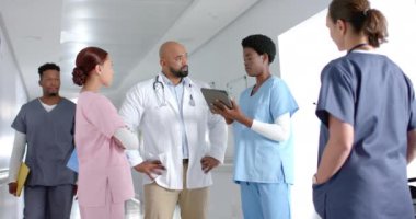 Çeşitli doktorlar işi tartışıyor ve hastanenin koridorunda tablet kullanıyorlar, ağır çekimde. Hastane, takım çalışması, iletişim, tıp, sağlık ve iş, değiştirilmemiş.