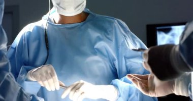 Ameliyathanede ameliyat önlüğü giyen çeşitli cerrahlar ağır çekimde ameliyat yapıyor. Hastane, ameliyat, takım çalışması, ilaç, sağlık ve iş, değiştirilmemiş.