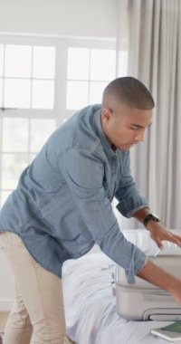 Parlak yatak odasında bavul hazırlayan mutlu bir İngiliz 'in dikey videosu. Seyahat, tatil, boş zaman ve yaşam tarzı, değiştirilmemiş..