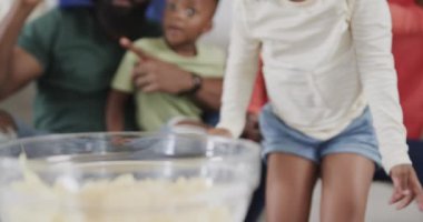 Oğlu ve kızı olan Afrikalı Amerikalı ebeveynler televizyonda bayrak sallayarak spor izliyorlar, ağır çekim. Spor, eğlence, aile, birliktelik, yaşam tarzı ve ev hayatı, değişmemiş..