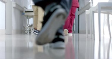 Hastanenin koridorunda yürüyen doktorların düşük seviyeli kesimi, ağır çekimde. Hastane, takım çalışması, ilaç, sağlık ve iş, değiştirilmemiş.