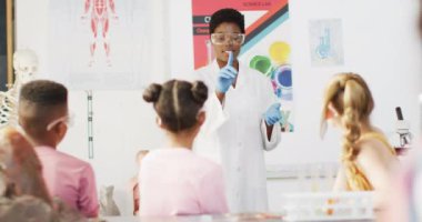 Sınıfta çeşitli öğrencileri olan Afrikalı Amerikalı kadın kimya öğretmeni, yavaş çekim. İlköğretim, eğitim, öğrenme ve kapsayıcılık kavramı.