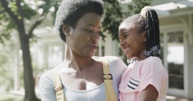 Mutlu Afro-Amerikan anne portresi güneşli bahçede kızını tutuyor, ağır çekimde. Aile, birliktelik, yaşam tarzı, doğa ve aile hayatı, değişmemiş..
