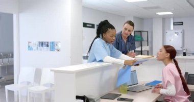Muhtelif doktorlar hastanede resepsiyonistle konuşuyor, ağır çekimde. Hastane, takım çalışması, iletişim, tıp, sağlık ve iş, değiştirilmemiş.