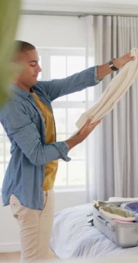 Parlak yatak odasında bavul hazırlayan mutlu bir İngiliz 'in dikey videosu. Seyahat, tatil, boş zaman ve yaşam tarzı, değiştirilmemiş..