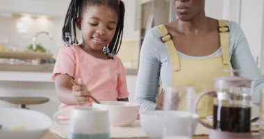 Happy african american mother and daughter enjoying meal in dining room, slow motion. Food, cooking, family, togetherness, lifestyle and domestic life, unaltered.