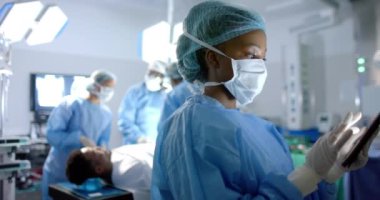 Ameliyathanede tablet kullanan Afro-Amerikan kadın cerrahın portresi. Ağır çekimde. Hastane, ameliyat, iletişim, ilaç, sağlık ve iş, değiştirilmemiş.