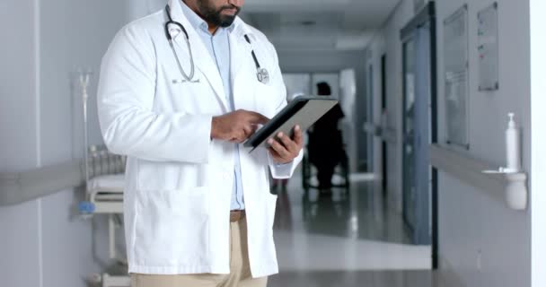 Biracial Male Doctor Wearing Lab Coat Stethoscope Using Tablet Corridor — Stock Video