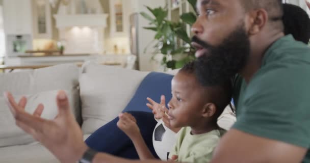 兴奋的非洲裔美国父母带着儿子和女儿在家里看电视上的运动 动作缓慢 生活方式和家庭生活 — 图库视频影像