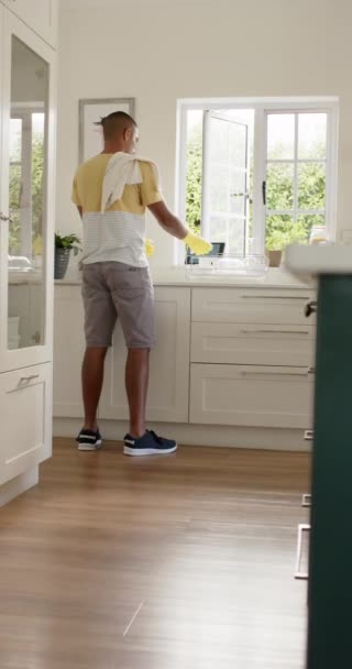 明るいキッチン スローモーションで料理を洗うAngloインド人男性の垂直ビデオ リラックス ライフスタイルと国内生活 変更なし — ストック動画