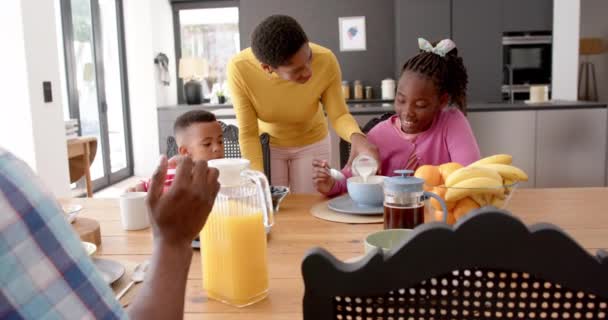 非裔美国人父母带着儿子和女儿在厨房的餐桌边吃早餐 动作缓慢 健康生活 生活方式和家庭生活 — 图库视频影像
