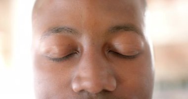 Portrait of happy african american casual businessman opening eyes in creative office in slow motion. Business and work, unaltered.