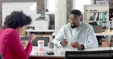 Çeşitli meslektaşlar ofiste ağır çekimde konuşuyor ve yemek yiyorlar. İş, yemek ve takım çalışması, değiştirilmemiş.