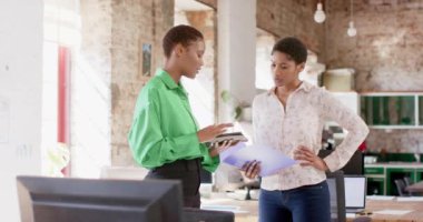 Mutlu Afro-Amerikan meslektaşları tablet kullanıyor ve ofiste işleri tartışıyor, ağır çekimde. İş, beyin fırtınası, teknoloji ve takım çalışması, değiştirilmemiş.