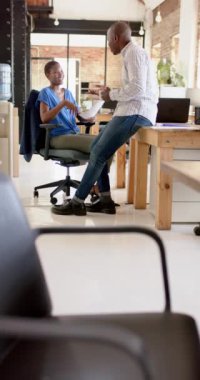 Afrika kökenli Amerikalı meslektaşların ofiste işleri tartıştıkları dikey video, yavaş çekim. İş, beyin fırtınası ve takım çalışması, değiştirilmemiş.