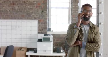 Happy african american casual businessman talking on smartphone in slow motion. Business, technology and work, unaltered.