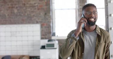 Happy african american casual businessman talking on smartphone in slow motion. Business, technology and work, unaltered.