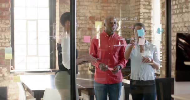 ハッピーアフリカ系アメリカ人の同僚は ガラスの壁にメモを取り 仕事について話し合い ゆっくりとした動きをします ビジネス ブレインストーミング チームワーク 変更されていない — ストック動画