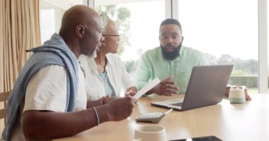 Afrikalı Amerikalı finans danışmanı ve evde konuşan yaşlı çift, yavaş çekim. Finans, emeklilik, iletişim, tavsiye, ev hayatı ve yaşlılar yaşam tarzı, değiştirilmemiş.
