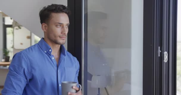 Boldog Biracial Férfi Kezében Kávéval Néz Ablakon Modern Lakásban Lassított — Stock videók