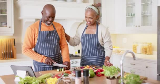 African American Senior Couple Aprons Preparing Meal Using Tablet Kitchen — Stock Video