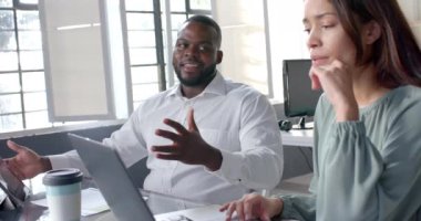 Laptop ve tablet kullanan mutlu meslektaşlar ofiste gelişigüzel konuşuyorlar, ağır çekimde. İş, iş, takım çalışması, iletişim ve günlük ofis, değiştirilmemiş.