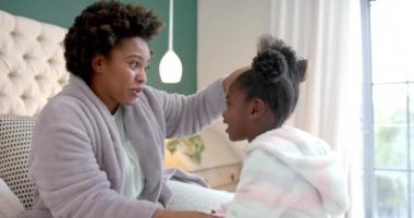 Mutlu Afro-Amerikan anneler yatak odasında kızlarının saçlarını tarıyor, ağır çekimde. Yaşam tarzı, aile, birliktelik, özgüven ve ev hayatı, değişmemiş..