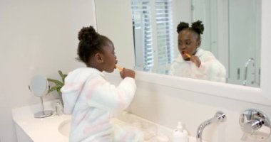 Afrikalı Amerikalı kız dişlerini banyoda fırçalıyor, ağır çekimde. Yaşam tarzı, kişisel bakım, hijyen ve ev hayatı, değişmemiş..