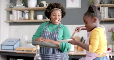Mutlu Afro-Amerikan anne ve kızı mutfakta krep pişiriyor, ağır çekimde. Yaşam tarzı, aile, birliktelik, yemek, aşçılık ve ev hayatı, değişmemiş..
