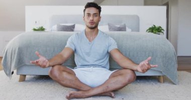 Yatak odasında yerde oturmuş yoga meditasyonu yapan rahat bir melez. Ağır çekimde. Refah, yaşam tarzı, kişisel bakım ve rahatlama, değişmemiş.