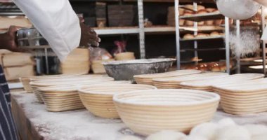 Fırın mutfağında çalışan çeşitli fırıncılar sepetlere ağır çekimde un döküyorlar. Takım çalışması, yemek, küçük işletme, fırın ve çalışma, değiştirilmemiş.