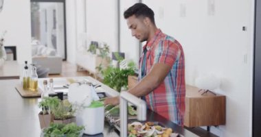 Çift ırklı bir adam yemek hazırlıyor, modern mutfakta sebze atıkları pişiriyor, ağır çekimde. Gıda, yemek pişirme, sağlıklı yaşam tarzı, ekoloji, geri dönüşüm ve ev hayatı, değiştirilmemiş.