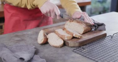 Kafkasyalı adamın elleri mutfakta ekmek kesiyor, ağır çekimde. Sağlıklı yaşam tarzı, yemek, yemek pişirme ve ev yaşamında değişiklik yok..