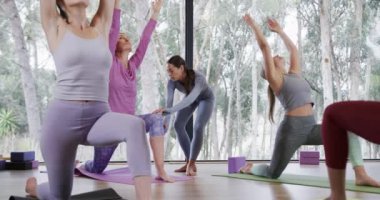 Yoga stüdyosunda hilal şeklinde poz veren kadınlara yardımcı olan çeşitli kadın eğitmenler. Değiştirilmemiş, yavaş çekim, yoga, egzersiz, fitness, zen, sağlıklı yaşam tarzı ve refah kavramı.