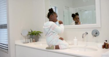 Afrikalı Amerikalı kız dişlerini banyoda fırçalıyor, ağır çekimde. Yaşam tarzı, kişisel bakım, hijyen ve ev hayatı, değişmemiş..