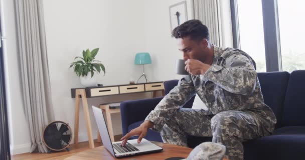 Biracial Mannlig Soldat Uniform Som Bruker Laptop Drikker Kaffe Stua – stockvideo