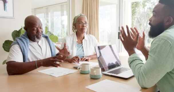 アフリカ系アメリカ人の財務顧問と高齢者のカップルが自宅で話して スローモーション コミュニケーション アドバイス 国内生活とシニアライフスタイル 変更なし — ストック動画